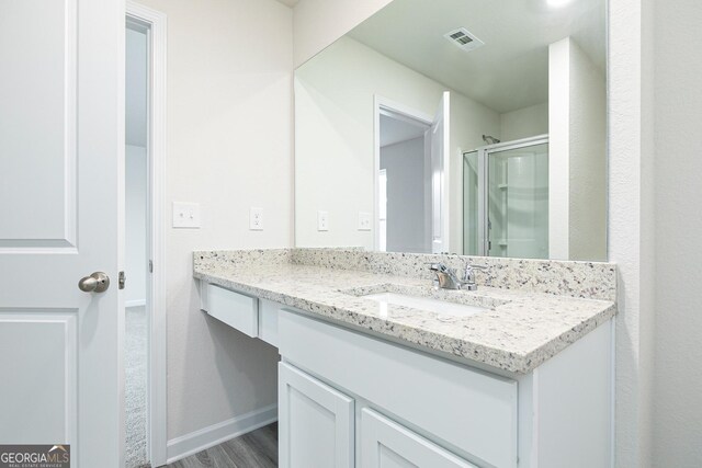 bathroom featuring hardwood / wood-style flooring, vanity, and a shower with door