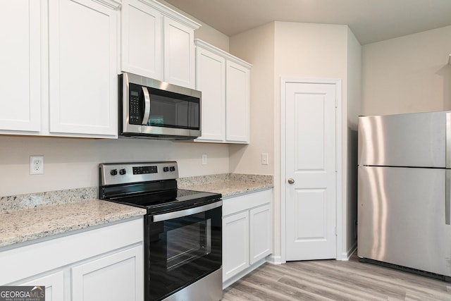 kitchen with white cabinets, light stone countertops, appliances with stainless steel finishes, and light hardwood / wood-style flooring