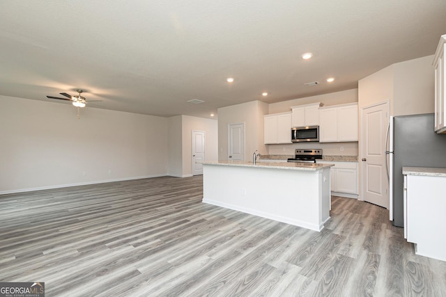 kitchen with a kitchen island with sink, light hardwood / wood-style flooring, white cabinets, and appliances with stainless steel finishes