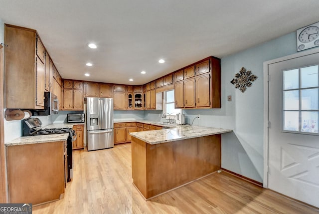 3615 Miller Bottom Rd, Loganville, GA 30052 - kitchen featuring light stone countertops, sink, light hardwood / wood-style flooring, kitchen peninsula, and appliances with stainless steel finishes