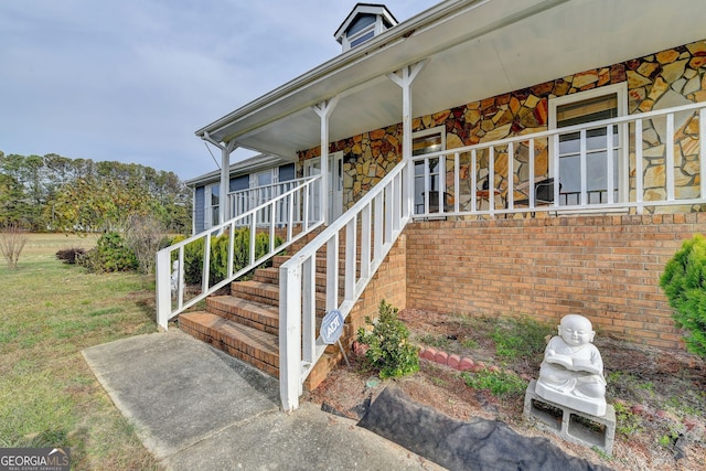 view of exterior entry with a porch and a yard