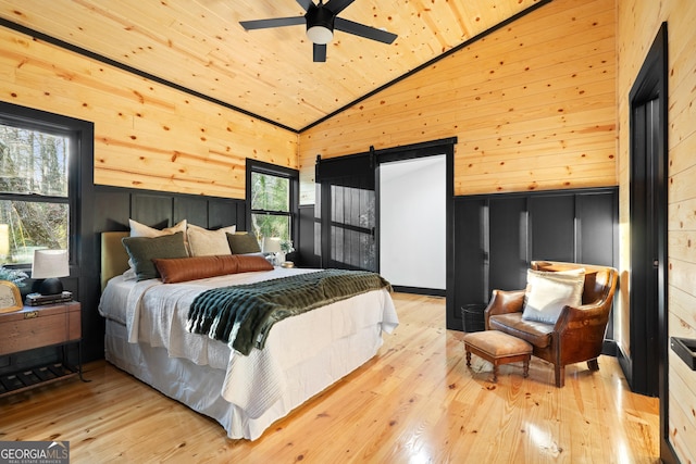 bedroom with wooden walls, ceiling fan, high vaulted ceiling, and multiple windows