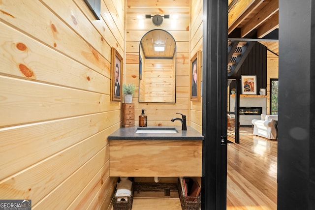 bathroom with hardwood / wood-style floors, vanity, and wooden walls