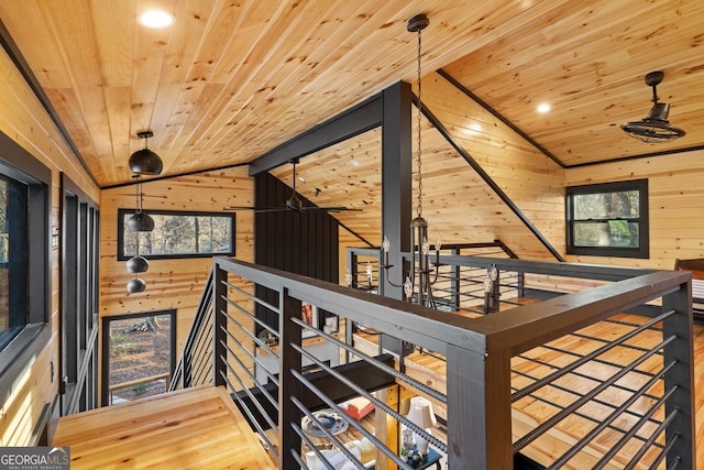 hall with wood walls, wooden ceiling, and lofted ceiling