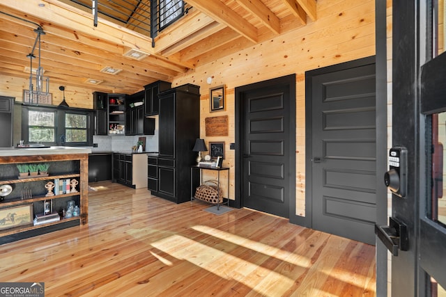 kitchen with a towering ceiling, light wood-type flooring, decorative light fixtures, and a skylight