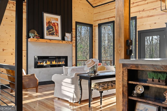 living area featuring wood walls, hardwood / wood-style floors, and high vaulted ceiling