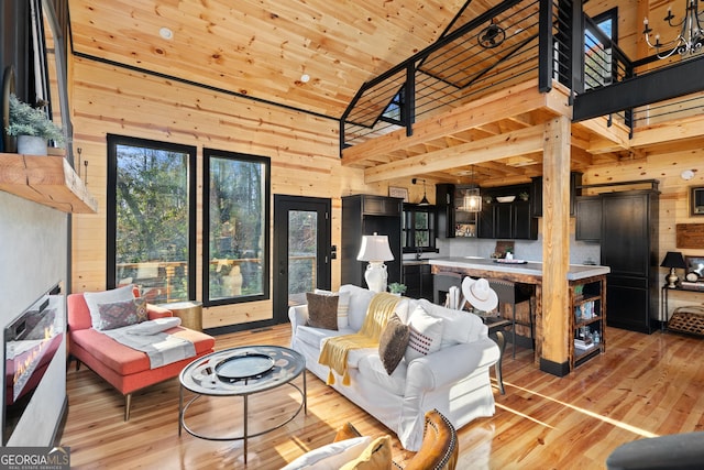 living room featuring light hardwood / wood-style flooring, high vaulted ceiling, wooden ceiling, and wood walls