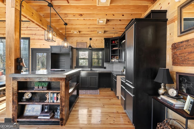 kitchen featuring light wood-type flooring, wood ceiling, sink, pendant lighting, and wood walls