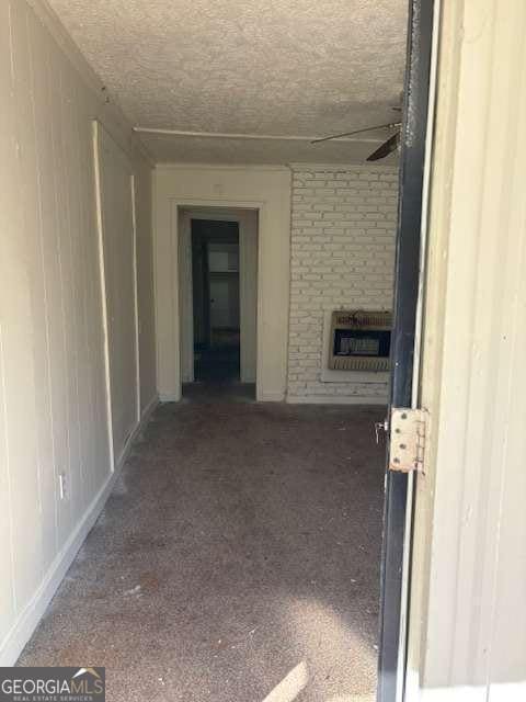 interior space with a fireplace, a textured ceiling, heating unit, and dark carpet