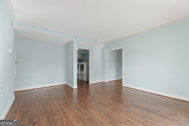 unfurnished living room featuring dark hardwood / wood-style floors, ornamental molding, and washing machine and clothes dryer