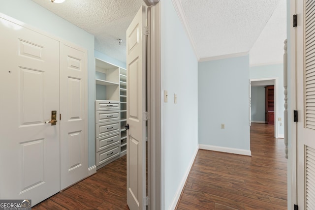 corridor with a textured ceiling, dark hardwood / wood-style floors, and ornamental molding