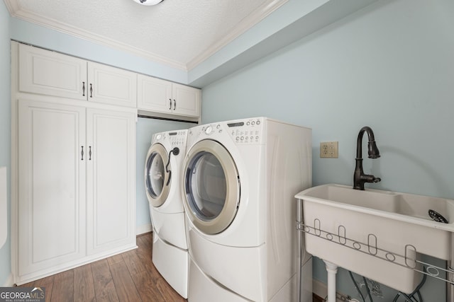 laundry area with cabinets, dark hardwood / wood-style flooring, ornamental molding, a textured ceiling, and separate washer and dryer