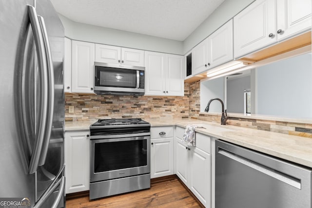 kitchen with white cabinets, light stone counters, and appliances with stainless steel finishes