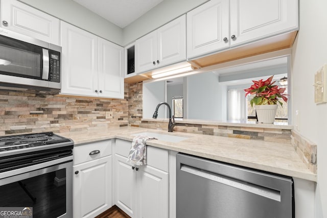 kitchen with white cabinetry, sink, light stone countertops, tasteful backsplash, and appliances with stainless steel finishes