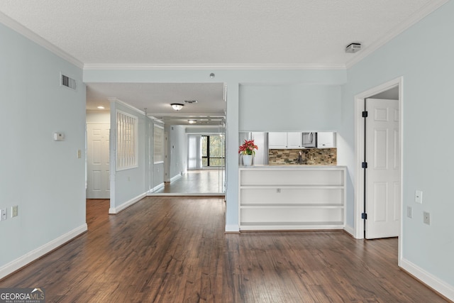 empty room with dark hardwood / wood-style flooring, a textured ceiling, and ornamental molding