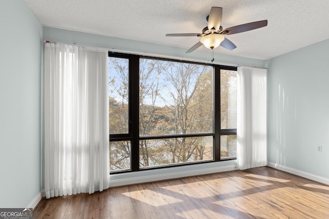 empty room featuring a wealth of natural light, ceiling fan, and a textured ceiling