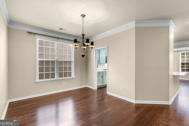 unfurnished dining area featuring a textured ceiling, dark wood-type flooring, an inviting chandelier, and crown molding