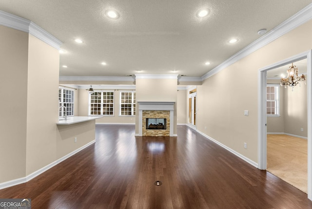 unfurnished living room with ornamental molding, a textured ceiling, a fireplace, a chandelier, and dark hardwood / wood-style floors