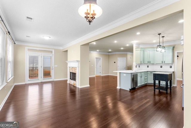 kitchen with a premium fireplace, stainless steel dishwasher, backsplash, decorative light fixtures, and green cabinetry