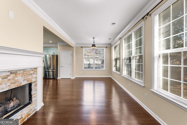 unfurnished living room with a stone fireplace, crown molding, a wealth of natural light, and dark wood-type flooring