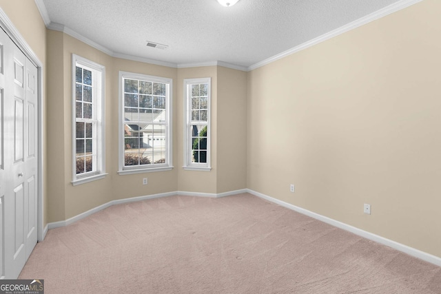 unfurnished room featuring a textured ceiling, ornamental molding, and light carpet