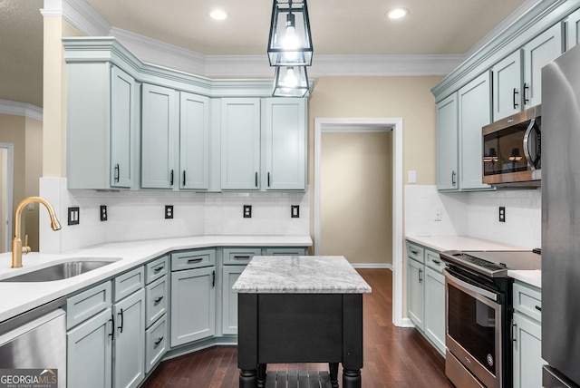 kitchen with a center island, crown molding, sink, appliances with stainless steel finishes, and decorative light fixtures