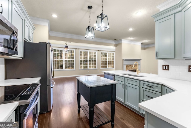 kitchen featuring hanging light fixtures, ornamental molding, sink, and appliances with stainless steel finishes