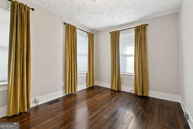 empty room with a textured ceiling and dark wood-type flooring