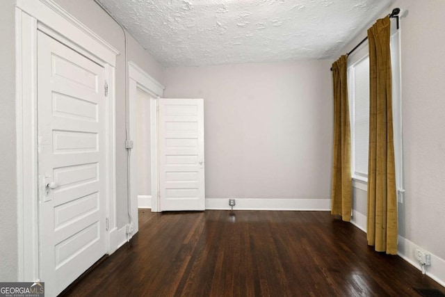 unfurnished bedroom featuring a textured ceiling and dark hardwood / wood-style floors