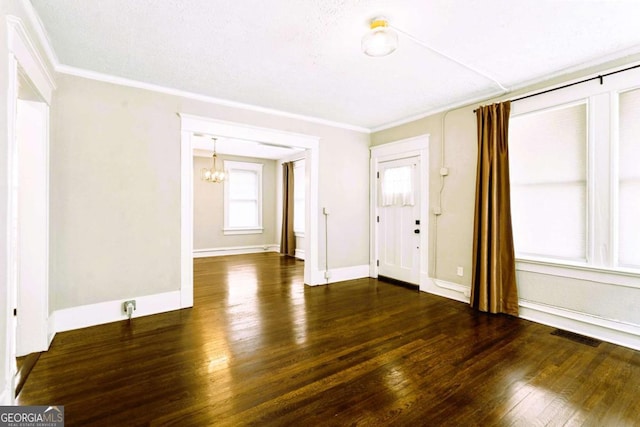 foyer entrance with ornamental molding, dark wood-type flooring, a textured ceiling, and a notable chandelier