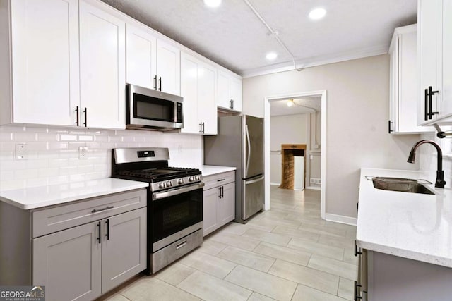 kitchen featuring light stone countertops, stainless steel appliances, gray cabinets, and sink