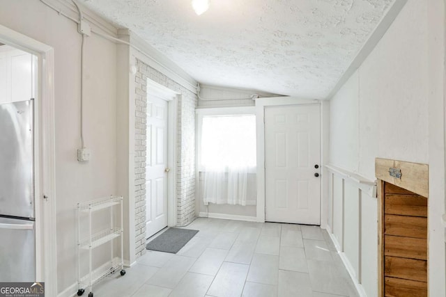 interior space with a textured ceiling, light tile patterned flooring, and lofted ceiling