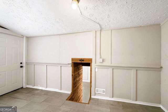 basement featuring tile patterned flooring and a textured ceiling