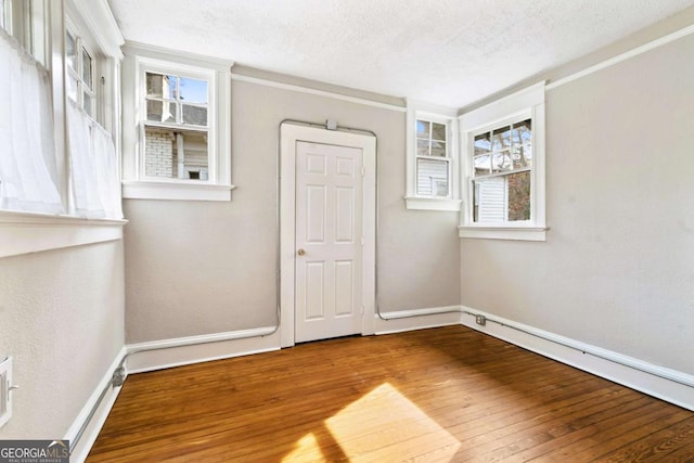 unfurnished room with plenty of natural light, wood-type flooring, and a textured ceiling