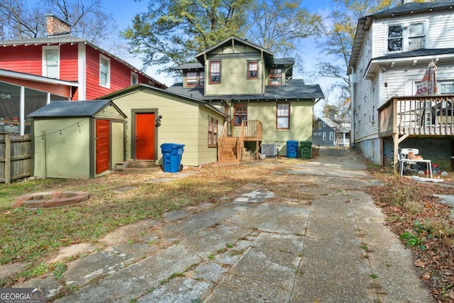 rear view of property with central AC unit and a shed