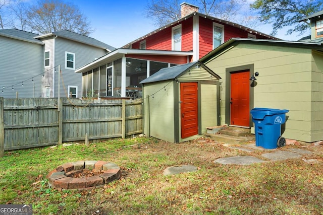 rear view of house featuring a sunroom and an outdoor fire pit