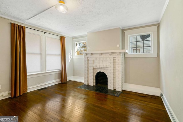 unfurnished living room featuring a textured ceiling, a fireplace, ornamental molding, and dark wood-type flooring