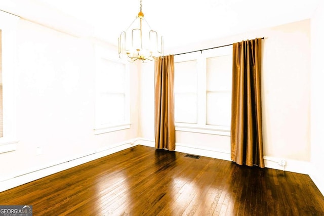 empty room featuring dark hardwood / wood-style floors and an inviting chandelier