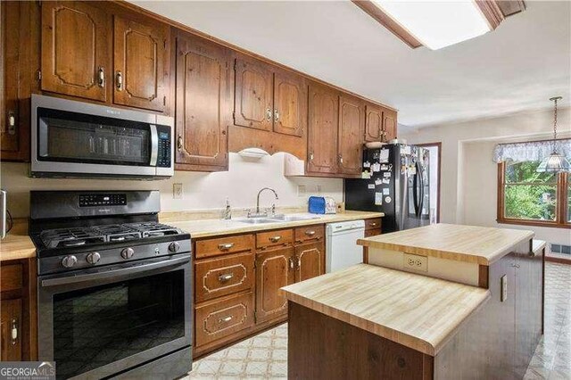 kitchen with stainless steel appliances, sink, decorative light fixtures, a kitchen island, and butcher block counters