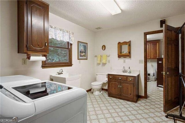 bathroom featuring vanity, a textured ceiling, toilet, and washer and clothes dryer