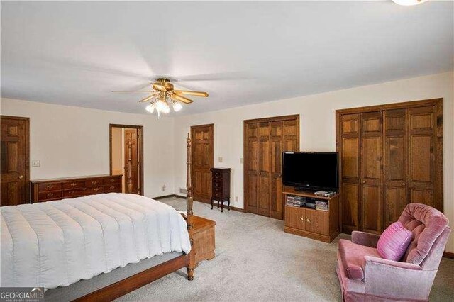 carpeted bedroom with ceiling fan and two closets