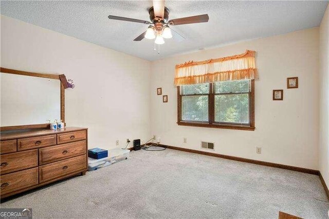 bedroom featuring ceiling fan, light colored carpet, and a textured ceiling