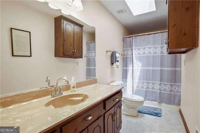 bathroom with tile patterned flooring, vanity, toilet, and a skylight