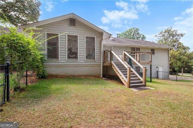 rear view of house with a deck and a lawn