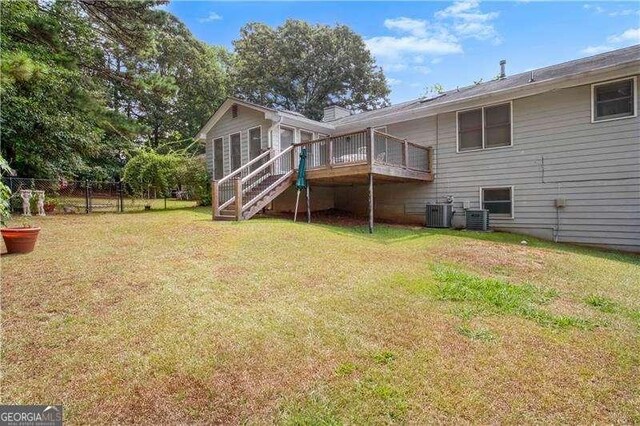 rear view of house with a lawn, a wooden deck, and central AC