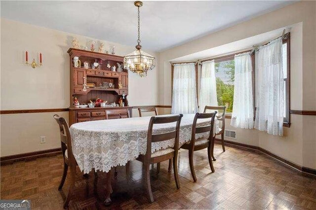 dining area with dark parquet flooring and a notable chandelier