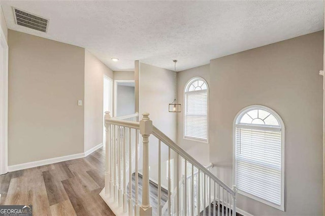 hall featuring a textured ceiling and light hardwood / wood-style flooring