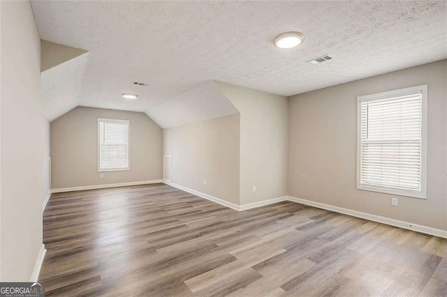 bonus room featuring a textured ceiling and light hardwood / wood-style flooring