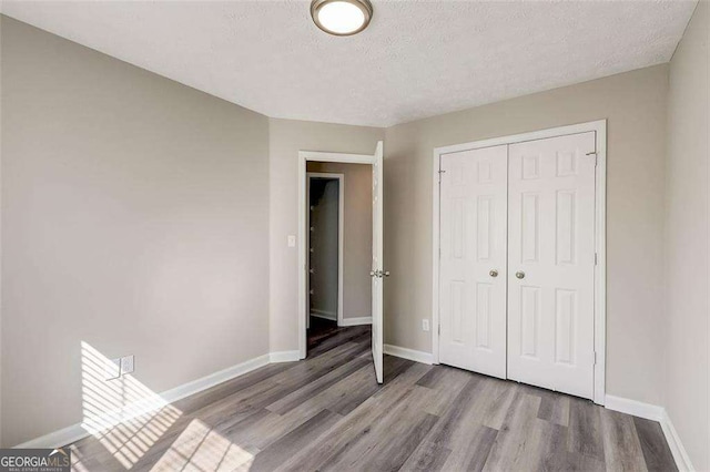 unfurnished bedroom with a closet, light hardwood / wood-style flooring, and a textured ceiling