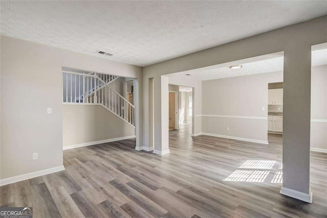 unfurnished living room featuring a textured ceiling and light hardwood / wood-style flooring